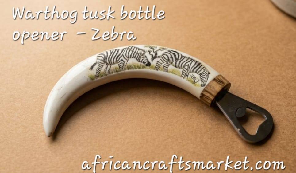 Detailed scrimshaw etching of zebras in the savanna on an authentic polished warthog tusk, displayed on a wooden stand